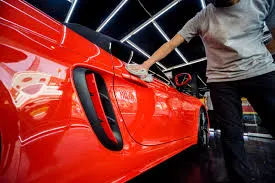 Detailer polishing a red sports car in the indoor facility