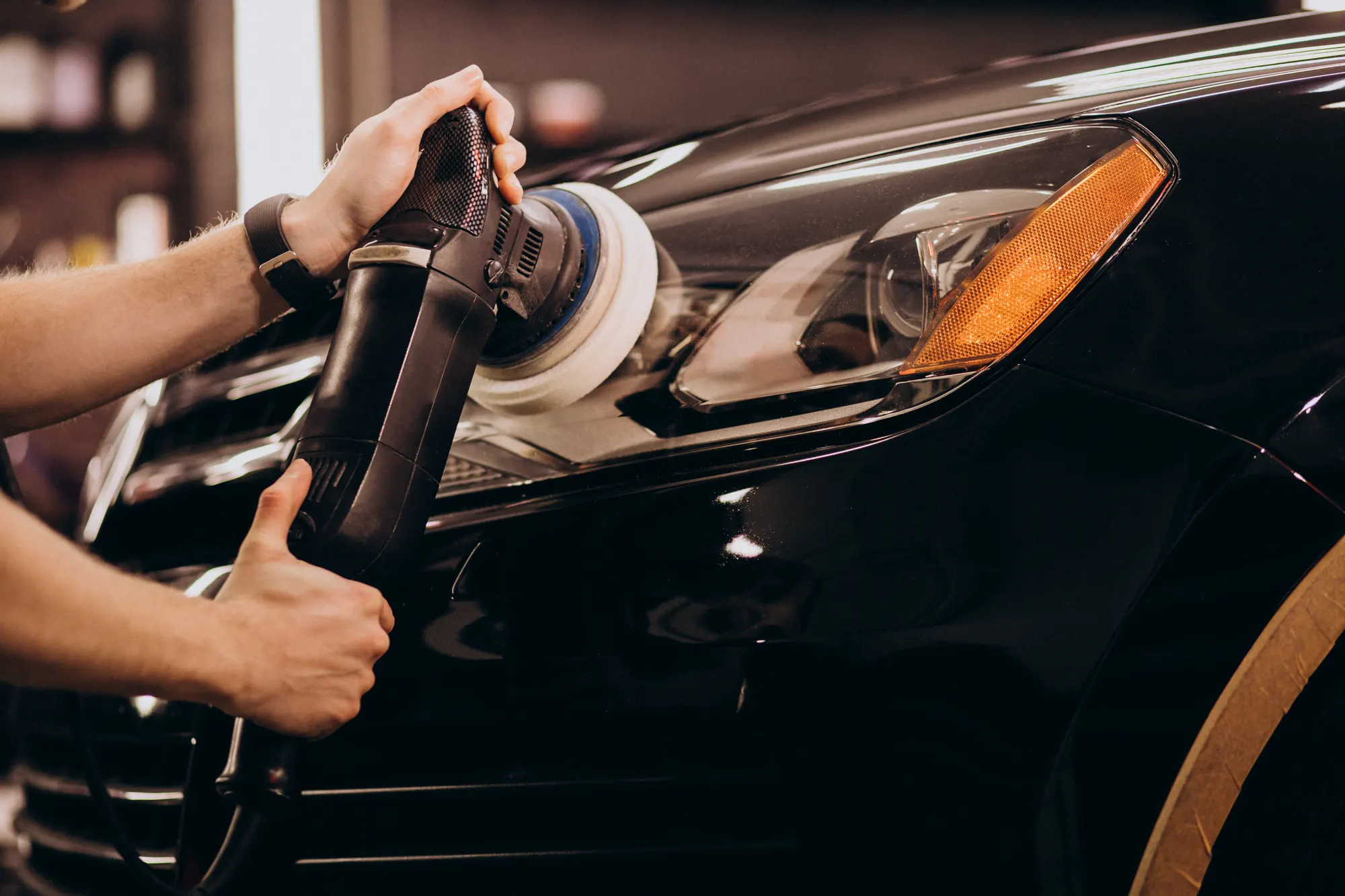 a guy detailing headlight of a car